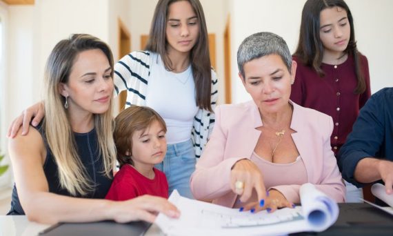 A family group reviewing real estate documents with a realtor indoors.